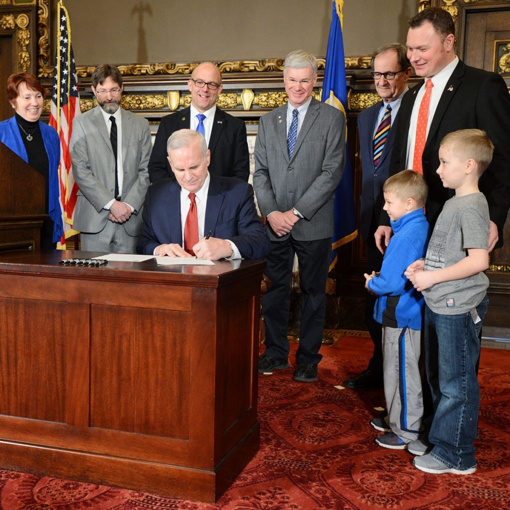Sen. Andrew Lang (R-Olivia) and his two children, right, watch as Gov. Mark Dayton signs his $35 million Rural Finance Authority legislation into law